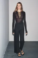 Jeans de tiro alto, pierna ancha y largo al tobillo, en denim celeste claro con efecto lavado. Presenta costura marcada en el centro de cada pierna y cierre frontal con cremallera y botón.