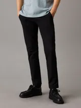 Pantalón chino negro de corte tapered, confeccionado en sarga de algodón elástica. Cuenta con cierre de botón y cremallera, bolsillos con ranura y bolsillos traseros de ojal.