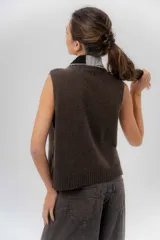 Chaleco de punto de lambswool color marrón, con cierre frontal y cuello alto en combinación de color gris y negro.