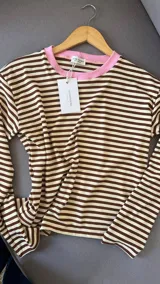 Remera de manga larga a rayas horizontales marrones y beige, con cuello redondo en contraste color rosa.