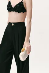 Bolso de mano tipo clutch con acabado nacarado y cierre de clip con detalle metálico dorado en la parte superior. Incluye cadena metálica para usar como bandolera.