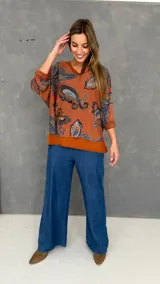 Blusa de algodón con diseño de doble capa, compuesta por una musculosa base y una capa superior de tejido liviano con estampado paisley en tonos naranja, celeste y marrón. Presenta un corte oversize y mangas tres cuartos.