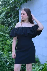 Vestido corto negro con escote off-shoulder con volados y corte ajustado.