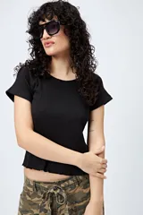 Remera blanca de punto acanalado, corte ajustado, mangas cortas raglán y ruedo ondulado.