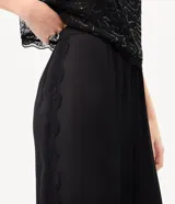 Pantalón balloon de crepé negro, de corte amplio y cintura elástica, con detalles de encaje en los laterales y puños inferiores elastizados.