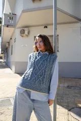 Chaleco tejido de punto con diseño de ochos, cuello redondo y sisa profunda. Presenta un detalle de terminación en color contrastante en el ruedo.