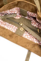Bolso tipo tote de gran tamaño confeccionado en material sintético con acabado efecto gamuza en color tostado. Presenta doble asa larga en tono contrastante y placa metálica pequeña con logo de la marca en la parte frontal.