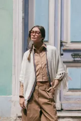 Poncho liviano de tejido de punto color blanco, con bordes decorados en crochet multicolor y flecos en el ruedo.