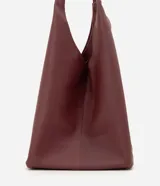 Cartera hobo grande marca Satinato, confeccionada en cuero con textura natural y color marrón oscuro. Presenta un diseño amplio y suave de estilo contemporáneo, con asas de hombro integradas y cierre interno con mosquetón.