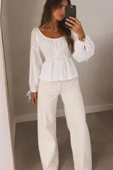 Blusa blanca de manga larga abullonada con tiras ajustables en los puños, escote redondo y cordón de ajuste en la cintura.