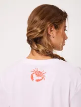 Remera celeste de corte holgado, con cuello redondo, manga corta y estampado frontal colorido de temática costera.