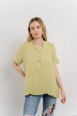 Blusa blanca de lino con escote en V abotonado y mangas cortas arremangadas.