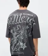 Remera de corte oversized color gris oscuro, con cuello redondo y manga corta. Presenta una estampa gráfica en la espalda que incluye un ángel, estrellas y el lettering 'No Mercy' junto a la frase 'Las calles no perdonan'.