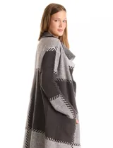 Cardigan largo tejido con diseño patchwork en tonos grises y negros. Presenta cuello con amplia solapa, diseño abierto sin botones y bolsillos delanteros amplios.
