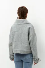 Tapado corto gris de paño, con cuello solapa grande, bolsillos de parche con solapa y mangas largas con puños anchos con presilla y aro metálico.