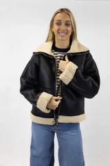 Campera estilo aviador de cuero sintético negro con interior y detalles de corderito en cuello, puños y ruedo. Cuenta con cierre frontal metálico.