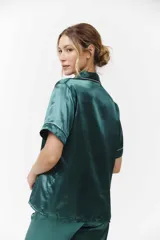Conjunto de pijama verde esmeralda de satén con ribetes blancos, compuesto por camisa de manga corta con botones y pantalón capri.