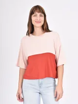 Remera de manga corta, corte holgado, con diseño de bloques de color: la parte superior y las mangas son de color rosa pálido, y el cuerpo inferior es de color terracota.