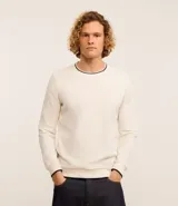 Sweater de manga larga color blanco hueso con textura acanalada vertical y cuello redondo con ribete negro contrastante.