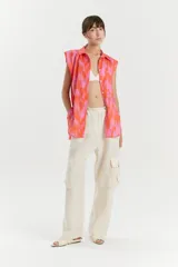 Camisa sin mangas de voile de algodón con estampado abstracto en tonos rosados y anaranjados. Tiene cuello camisero, cartera con botones a la vista, tajos laterales y bolsillo de parche en el delantero.
