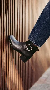 Bota corta de cuero color chocolate, con diseño minimalista, taco cuadrado de 4 cm y una hebilla metálica decorativa en el tobillo sobre una banda de gamuza.