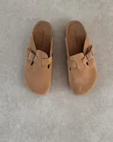 Zueco tipo clog de gamuza color camel, con tira ajustable y hebilla metálica. La plantilla lleva grabado el texto "LUCY IN THE SKY".