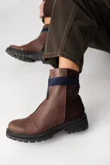 Bota corta de cuero color marrón con cierre frontal, suela track negra y paneles laterales en gamuza de un tono más oscuro.