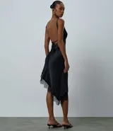 Vestido midi de satén negro con escote corazón, breteles finos ajustables y ruedo asimétrico decorado con encaje. Presenta un diseño fluido y elegante con cierre posterior.