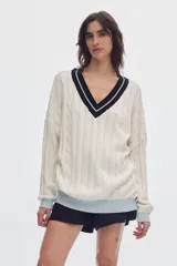 Sweater de punto oversized de color marrón, con escote en V, detalles de ochos y puños, cuello y ruedo en tono celeste y blanco.