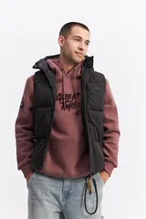 Chaleco puffer acolchado color azul marino, con capucha fija, cierre frontal con solapa de botones a presión y bolsillos laterales con cierre. Presenta un parche con el logo de la marca en el pecho.