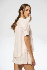 Camisa de lino a rayas verticales rojas y blancas, con cuello mao, escote en V, mangas cortas abullonadas y botones de nácar ocultos.