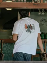 Remera blanca de manga corta con estampado en la espalda que ilustra a varios animales jugando al truco.