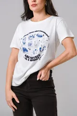 Remera de algodón blanca con cuello redondo y mangas cortas. Presenta un estampado frontal en color azul con ilustraciones de cristales y la frase 'Energy flows where intention goes' junto a 'Abundance is a mindset'.