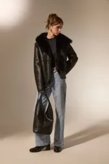 Bolso tipo hobo de gran tamaño, color negro, con diseño trenzado en la parte frontal y base lisa. Cuenta con un asa integrada para llevar al hombro.