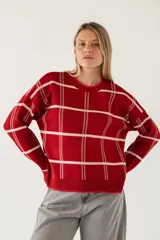 Sweater de punto color rojo con diseño de cuadrícula en color blanco, de corte holgado, cuello redondo y mangas largas con puños acanalados.