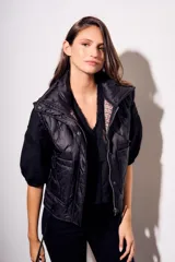Chaleco negro con cierre frontal y cuello alto, de corte al cuerpo y diseño acolchado. Reversible, con interior a cuadros.