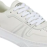 Championes Lacoste modelo L004, de diseño urbano en color blanco con detalles en gris claro. Presentan una silueta de perfil bajo con paneles de lona y refuerzos de gamuza en la puntera y el talón. Incluyen el icónico logo del cocodrilo metálico en el lateral del talón y una suela de goma vulcanizada.