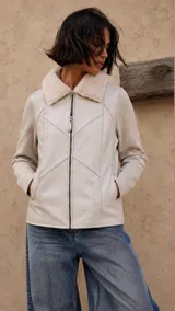 Campera de cuero y lana color crudo, con cierre frontal, bolsillos laterales y cuello de corderito sintético.