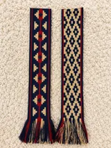 Faja tejida en telar de mano con diseño geométrico multicolor en tonos azul marino, beige y rojo, con flecos en los extremos.