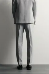 Pantalón de traje slim fit color gris, con bolsillos frontales, bolsillos traseros de doble vivo, trabillas para cinturón y cierre frontal con cremallera y botón.