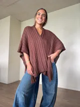 Ruana tejida de punto marrón con detalle de lurex, escote en V y diseño amplio y envolvente.