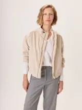 Campera tipo bomber de pana color beige, con cuello mao, cierre frontal metálico y bolsillos laterales. Presenta un diseño de corte relajado y bordado en la espalda.