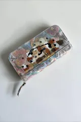 Billetera de cuero natural con diseño pintado a mano, cierre perimetral y múltiples compartimentos interiores.