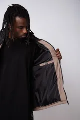 Campera puffer de diseño bicolor, con cuerpo en tono beige y canesú superior en color negro. Presenta cuello alto, cierre frontal completo y puños elásticos.