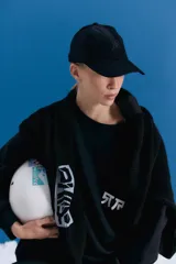 Gorra tipo cap confeccionada en corderoy negro, con isologo bordado a tono en el frente y tira de ajuste con hebilla metálica en la parte posterior.