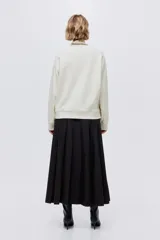 Buzo oversized color crema con cuello redondo acanalado. Presenta un estampado frontal en negro con el texto "VERMONT SKI CLUB Montpelier 1970" y un logo de montaña. Tiene hombros caídos y remates acanalados en puños y bajo.