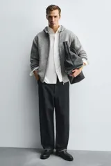 Bota corta estilo Chelsea de cuero liso negro, con elásticos laterales y tirador trasero para calce. Presenta horma redonda y suela con ligero tacón.