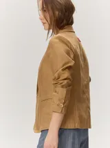 Blazer de lino color negro con pespuntes en contraste de hilo tostado, cuello solapa amplia, cierre frontal con un botón de madera y bolsillos aplicados.