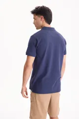 Chomba de piqué color blanco, con cuello polo y cierre frontal con tres botones.