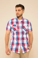 Camisa de manga corta con estampado de cuadros en tonos rojo, azul y blanco. Presenta cuello clásico, cierre frontal con botones y dos bolsillos delanteros con solapa en el pecho.